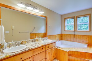 Un baño con paneles de madera, lavamanos doble, espejo grande y bañera.