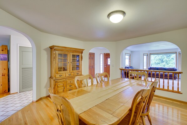 Un comedor espacioso con una gran mesa de madera y sillas, un aparador de madera y vistas a un balcón con barandilla.
