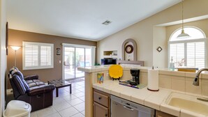 A compact kitchen with a dishwasher, a coffee maker, and a yellow tray.