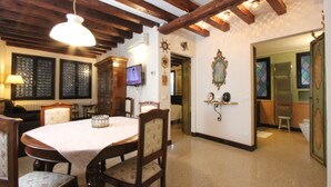 Un comedor con mesa y sillas de madera, un televisor y un pasillo que lleva a un baño.