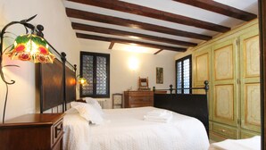 Un dormitorio con una cama grande, cabecera de madera, una mesita de noche, un aparador y un armario verde.