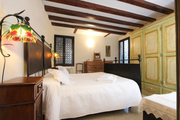 Un dormitorio con una cama grande, cabecera de madera, una mesita de noche, un aparador y un armario verde.