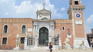Un edificio histórico con una imponente torre de reloj, estatuas y una entrada majestuosa.