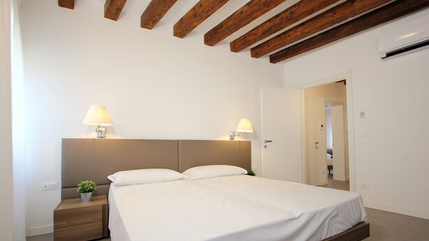 A bedroom with a bed, nightstands, and two wall-mounted lamps. - Apt. Canaletto (Residence Artisti) (Venecia)