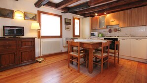 A kitchen with wooden cabinets, a dining table with chairs, a built-in oven, and a window with a view.