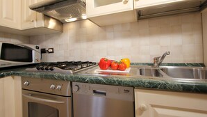 Une cuisine avec des meubles blancs, un four à micro-ondes, une cuisinière, un lave-vaisselle et un évier.
