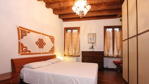 A bedroom with a wooden bed, a nightstand, a dresser, and a chandelier. - Apartment Laura (near Biennale Arsenale) (Venecia)