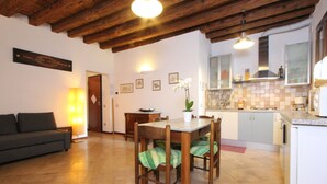 A dining area with a wooden table and chairs, a sofa, and a kitchen in the background. - Apartment Laura (near Biennale Arsenale) (Venecia)