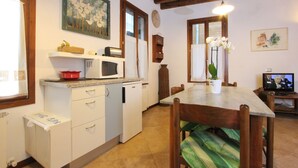 A compact kitchen with a microwave, sink, and a dining area with a table and chairs. - Apartment Laura (near Biennale Arsenale) (Venecia)
