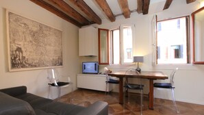 Un salon avec un canapé, une table à manger et des chaises, un téléviseur et une grande carte accrochée au mur.