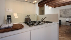 Une cuisine moderne équipée d’une cuisinière à gaz, d’une bouilloire et d’une planche à découper en bois.