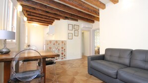Un salon avec un plafond en bois, un canapé gris et un coin repas comprenant une table et des chaises.