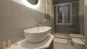 Een moderne badkamer met een groot wit wastafel, een douche met glazen wanden en een toilet.