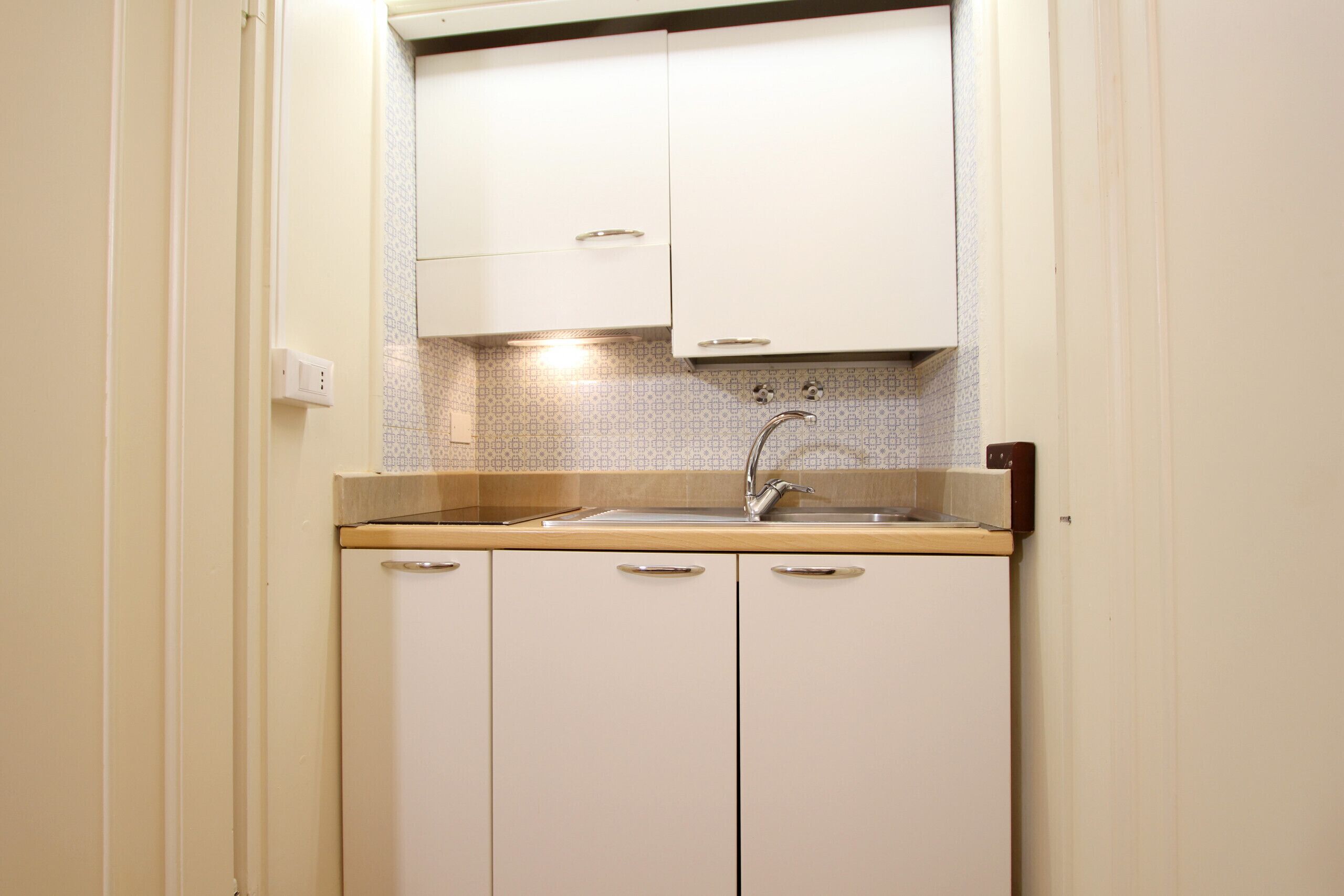 A compact kitchen with a sink, cabinets, and a backsplash.