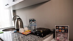 En köksbänk med en kaffebryggare, två koppar, ett fat med snacks, vattenflaskor och en skylt med en QR-kod.