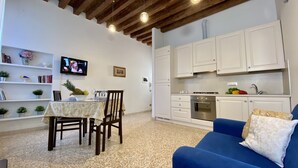 A compact living space with a dining area, kitchenette, and a blue sofa. - Apartment Canova Canal View (Venecia)