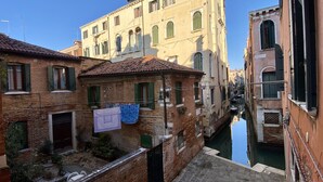 A narrow Venetian canal flanked by historic buildings with brick facades and arched windows. - Apartment Canova Canal View (Venecia)
