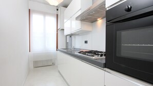 Une cuisine moderne avec un four noir, des plans de travail en acier inoxydable et des meubles blancs.