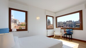 A hotel room with a large bed, two windows, a chair, a small table, and a television. - Apartment Altana, Amazing Grand Canal View (Venecia)