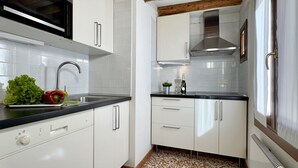 A modern kitchen with white cabinets, a stainless steel sink, and a black countertop. - San Giovanni (Venice Historical Centre) (Venecia)