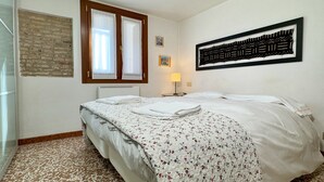 A bedroom with a bed, a window, a radiator, a lamp, and a wall art piece. - San Giovanni (Venice Historical Centre) (Venecia)