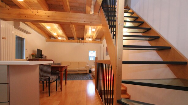 Un vaste espace de vie agrémenté d’un escalier en bois et d’un coin cuisine.