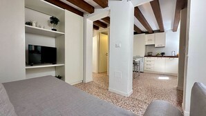 A compact living space with a kitchenette, a television, and a bed.