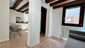 A compact kitchen with a dining area, a radiator, and a window with a view.
