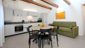 Una cocina moderna con armarios blancos, techo de madera y comedor con mesa y sillas redondas.