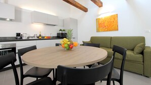 Una cocina moderna con armarios blancos, una mesa de comedor de madera y un sofá verde.