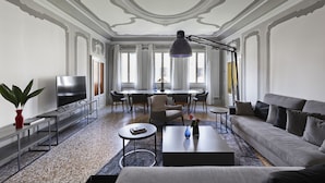 A modern living room with a sofa, coffee table, TV, and dining area.