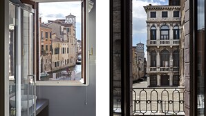 A view from a window of a building with a balcony overlooking a street with historic buildings.