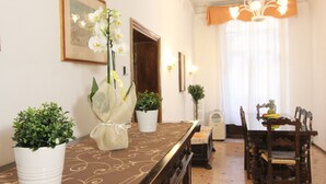 Un espace repas comprenant une longue table, des chaises, un lustre et des plantes en pot.