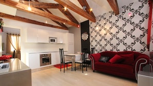 A modern kitchen with white cabinets, a red sofa, and a dining area. - Apt. Gold Design (300m from Rialto´s Bridge) (Venecia)