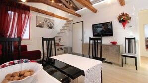 A dining area with a table, chairs, and a bowl of nuts. There is a staircase leading to another room, a television mounted on the wall, and wooden beams on the ceiling. - Apt. Gold Design (300m from Rialto´s Bridge) (Venecia)
