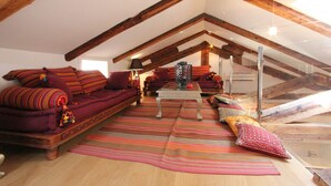 A cozy loft bedroom with exposed wooden beams, a large window, and a plush red sofa with colorful pillows. - Apt. Gold Design (300m from Rialto´s Bridge) (Venecia)