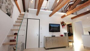 A modern interior with a staircase, a flat-screen TV, and a dining area. - Apt. Gold Design (300m from Rialto´s Bridge) (Venecia)
