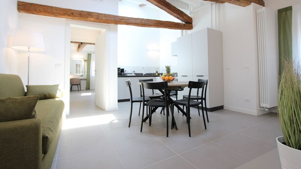 A modern living room with a dining area, featuring a sofa, dining table, chairs, and a potted plant. - Residence dei 3 Artisti (Venecia)