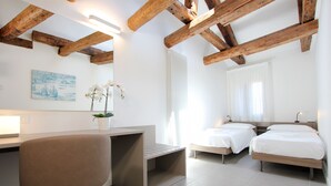 A modern bedroom with a wooden ceiling, two beds, a desk, and a chair. - Residence dei 3 Artisti (Venecia)