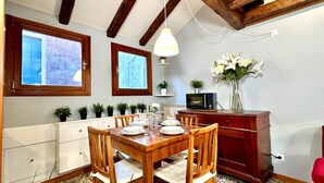 Un coin repas avec une table en bois, dressée pour quatre personnes, flanquée de meubles de rangement et d’un téléviseur.