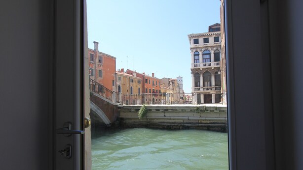 A view from inside a building looking out at a canal with buildings along the water.