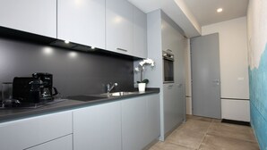 A modern kitchen with grey cabinets, a black coffee maker, a sink, and a potted orchid.