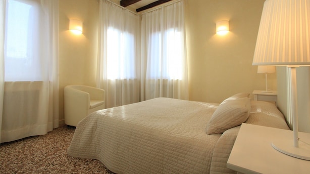 A hotel room with a bed, a chair, a nightstand, and a lamp. - Venice Amazing View (St. Mark´s Square 700m) (Venecia)