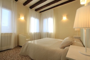 Ein Hotelzimmer mit Bett, Stuhl, Nachttisch und Lampe.