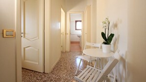 A hallway with white doors, a white table with chairs, and a potted plant. - Venice Amazing View (St. Mark´s Square 700m) (Venecia)