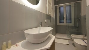Een moderne badkamer met een groot wit wastafel, een douche met glazen wanden en een toilet.