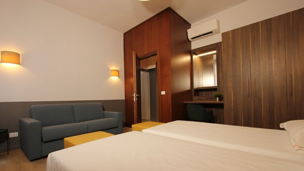 Een hotelkamer met een bed, een bank, een bureau en een spiegel.