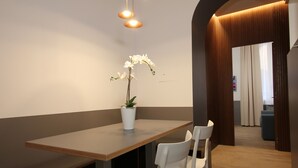 Een moderne eethoek met een houten tafel, witte stoelen en een orchidee in een pot.