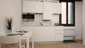 A modern kitchen with white cabinets, a stainless steel oven, and a window with a view of a brick building. - Rialto Studio (300mt from Rialto´s Bridge) (Venecia)