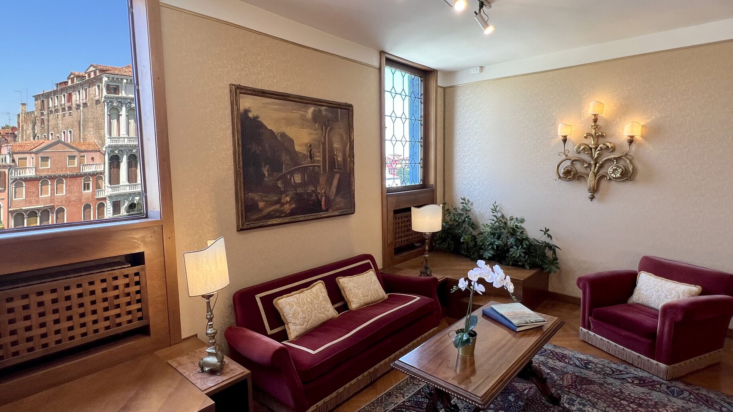 A living room with a red sofa, a wooden coffee table, and a painting on the wall.
